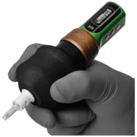 Grip nero per tatuaggi con elemento verde, tenuto in un guanto grigio