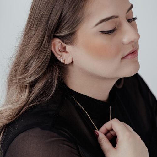 Donna con piercing all'orecchio, decorazione dorata Push Fit Crystal Lovely Eye, top nero