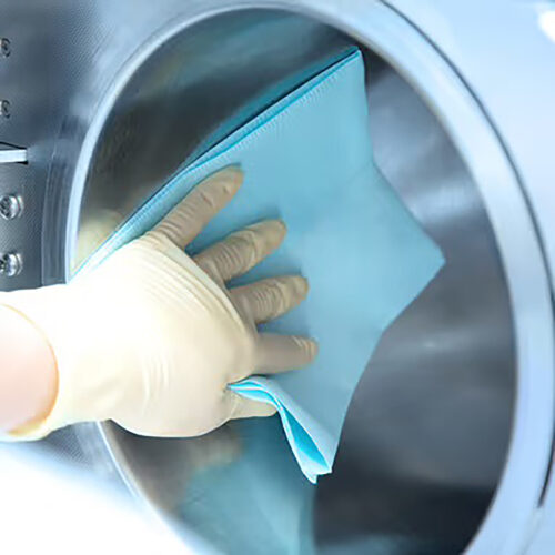 Mano con guanto pulisce caldaia con panno blu, superficie metallica