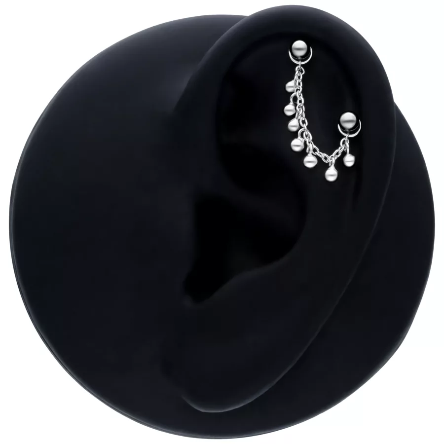 Catena piercing nera con piccole sfere, lunghezza 20mm, su un modello di orecchio