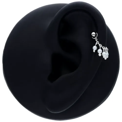 Collana piercing nera con piccole perle su un orecchio su sfondo nero
