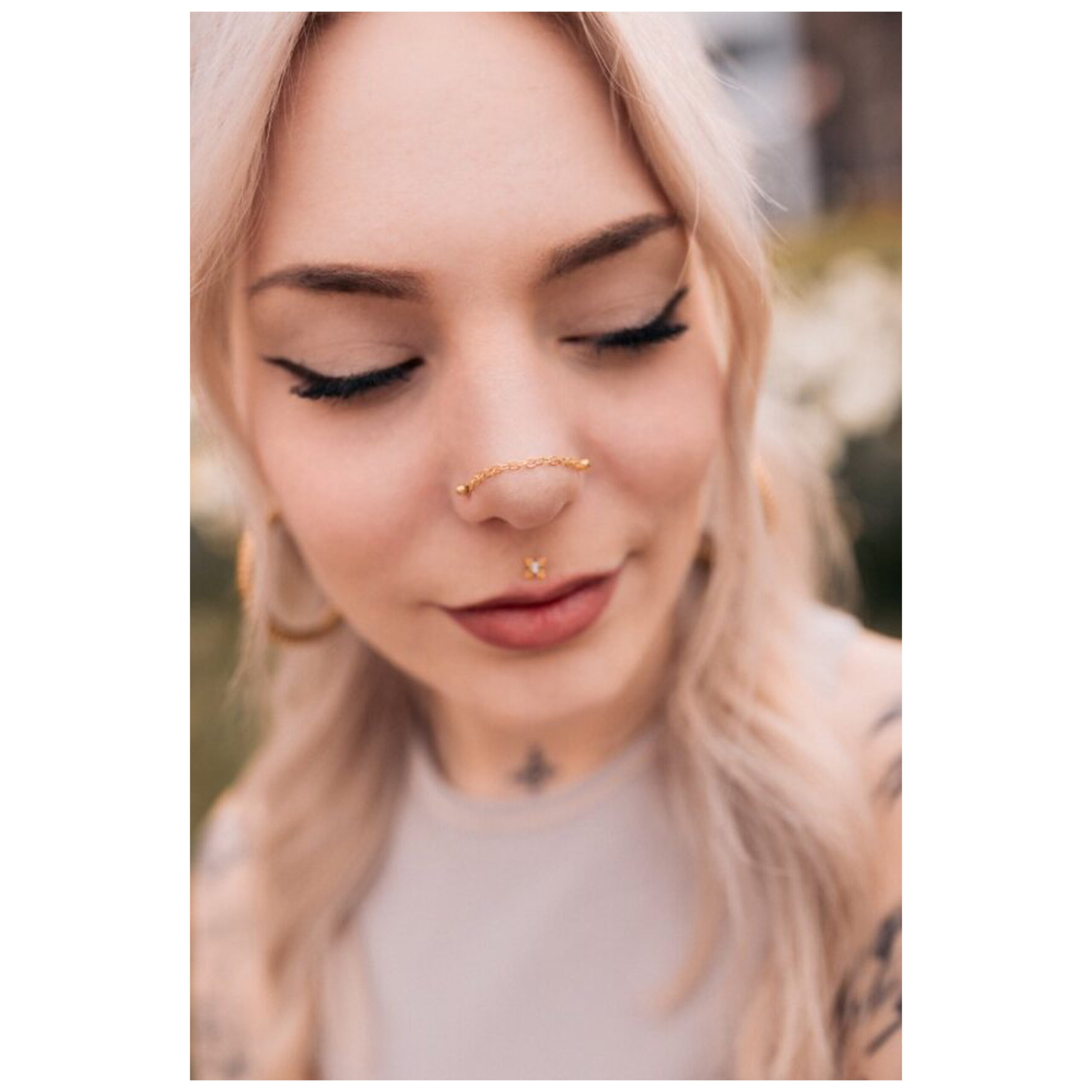 Donna con catena piercing dorata su naso e orecchio, all'aperto