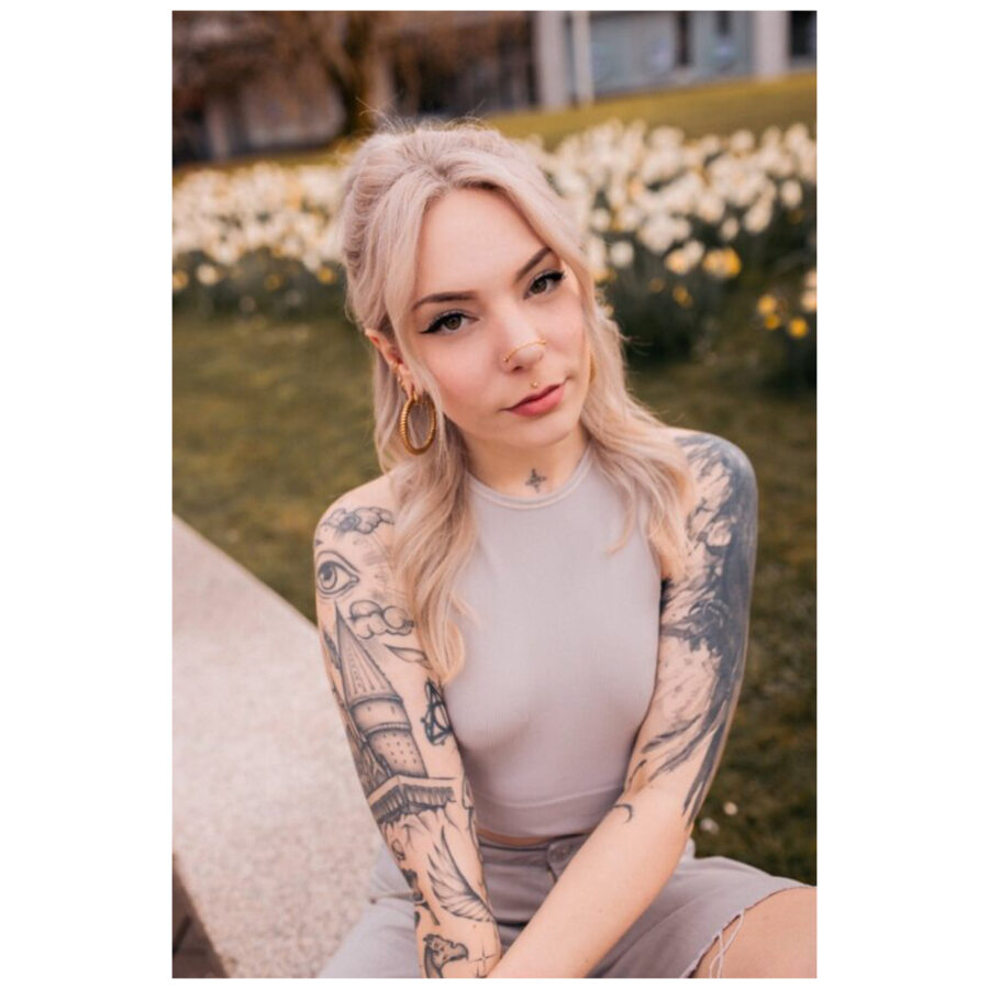 Donna con tatuaggi indossa una catena piercing in argento al parco
