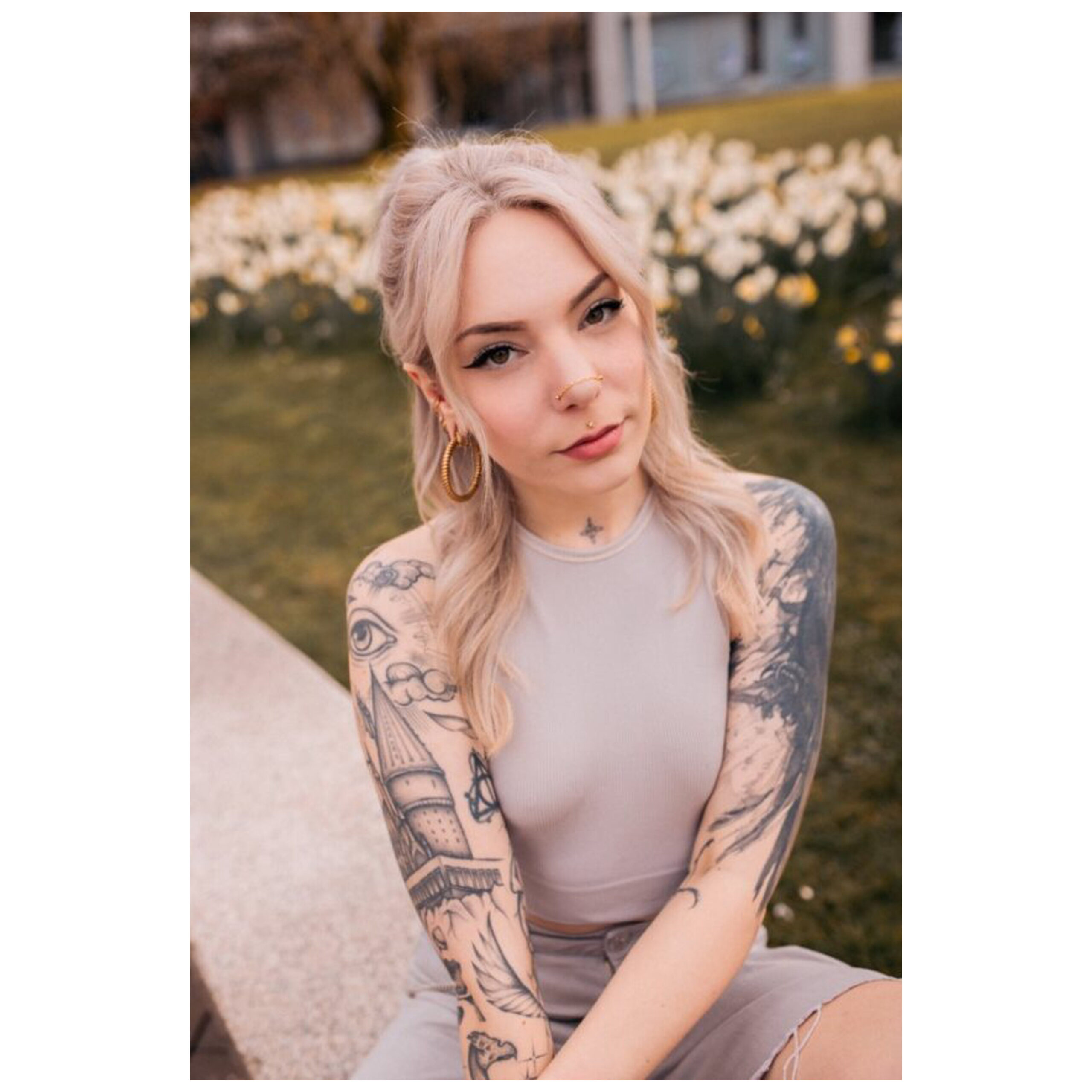 Donna con tatuaggi indossa una catena piercing in argento al parco