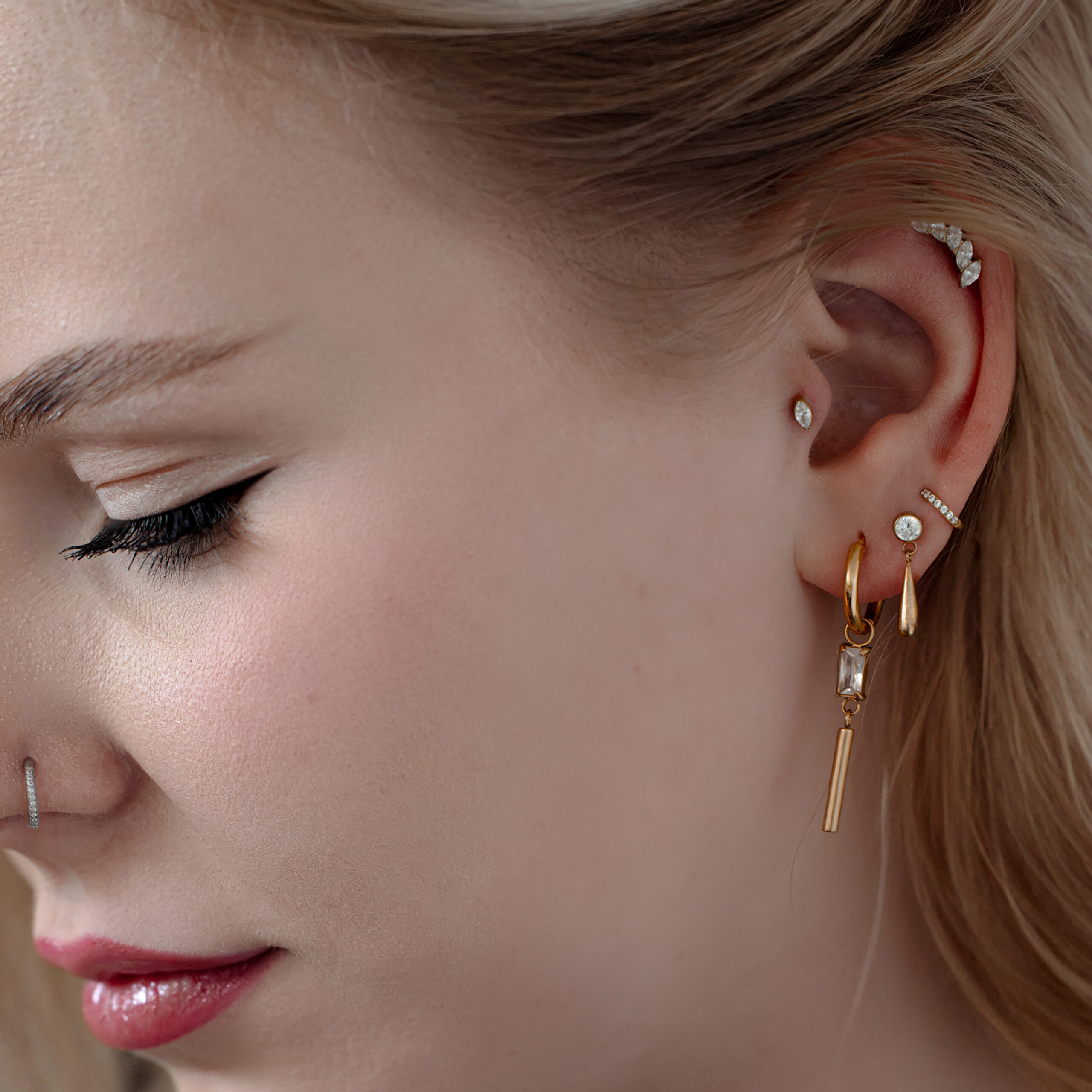 Primo piano di un orecchio con Push Fit Crystal Drop rosé dorato e altri piercing