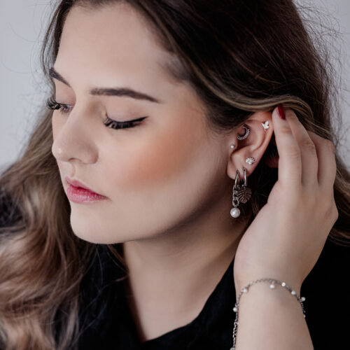 Donna con un accessorio Push Fit Pearl in argento nell'orecchio su sfondo neutro