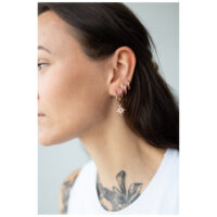 Donna con Little Polar Star Hoops in oro rosa all'orecchio su sfondo neutro