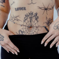 Donna indossa doppie catene per il ventre in argento e oro su pancia tatuata