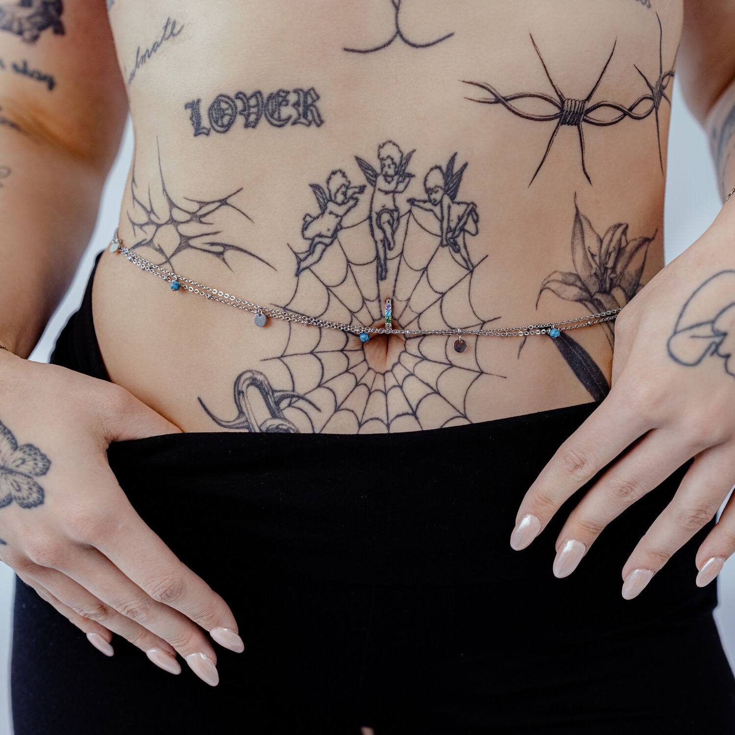 Donna indossa doppie catene per il ventre in argento e oro su pancia tatuata