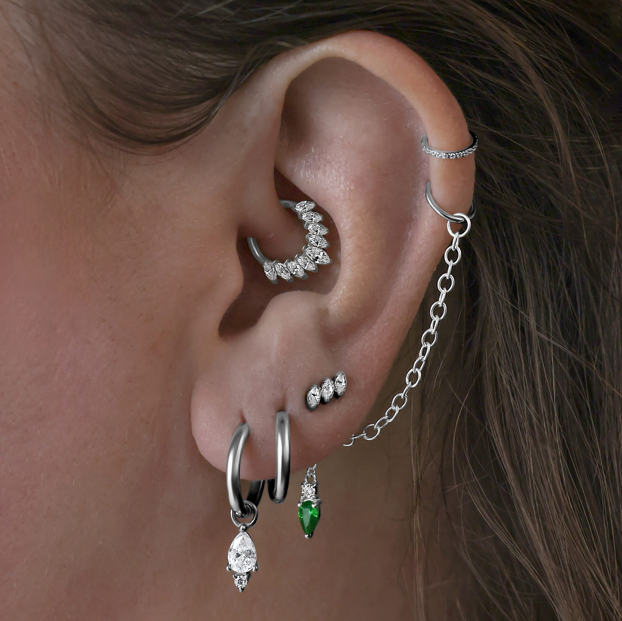 Collana piercing con cristalli verde smeraldo indossata all'orecchio, collegata con catena d'argento
