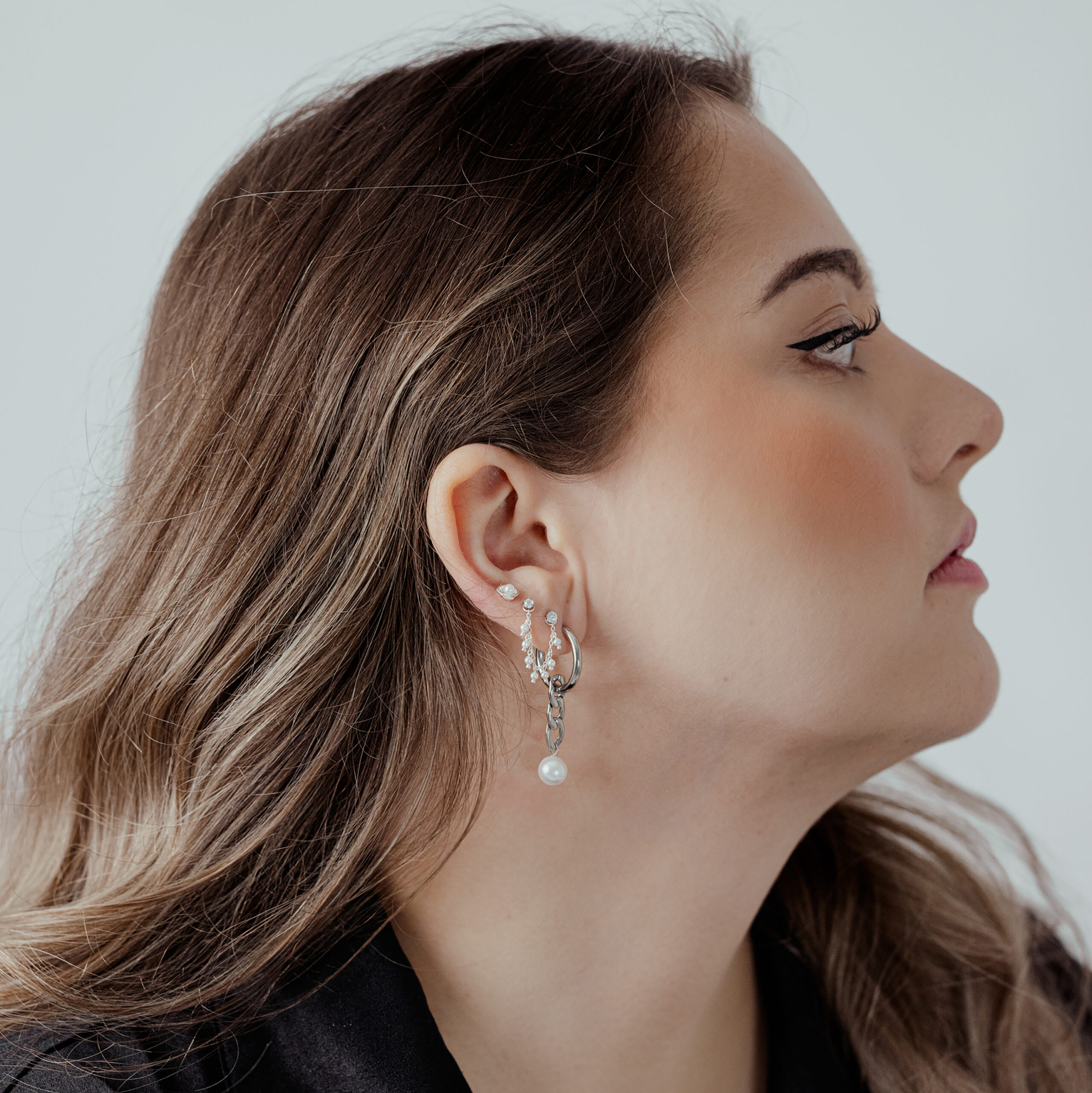 Donna con punta Push Fit in argento nell'orecchio, vista laterale su sfondo bianco