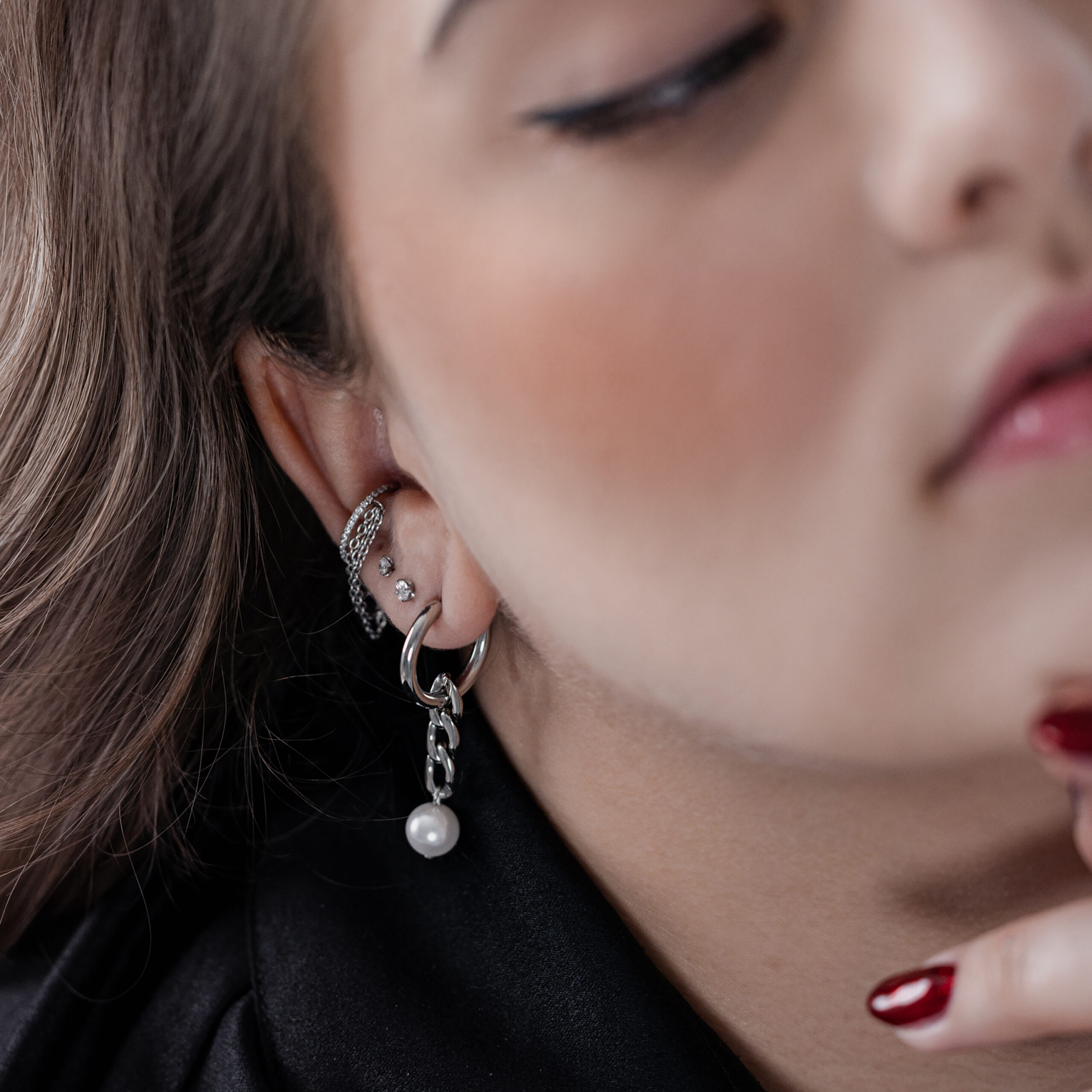 Primo piano di cerchi d'argento con pendente di perla all'orecchio di una persona