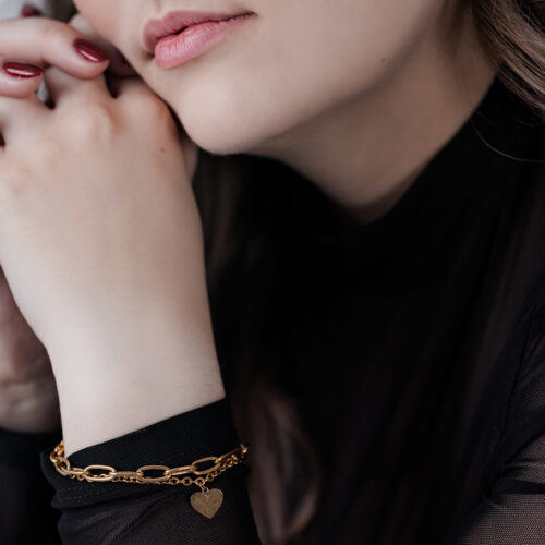 Donna con bracciale cuore dorato su sfondo nero