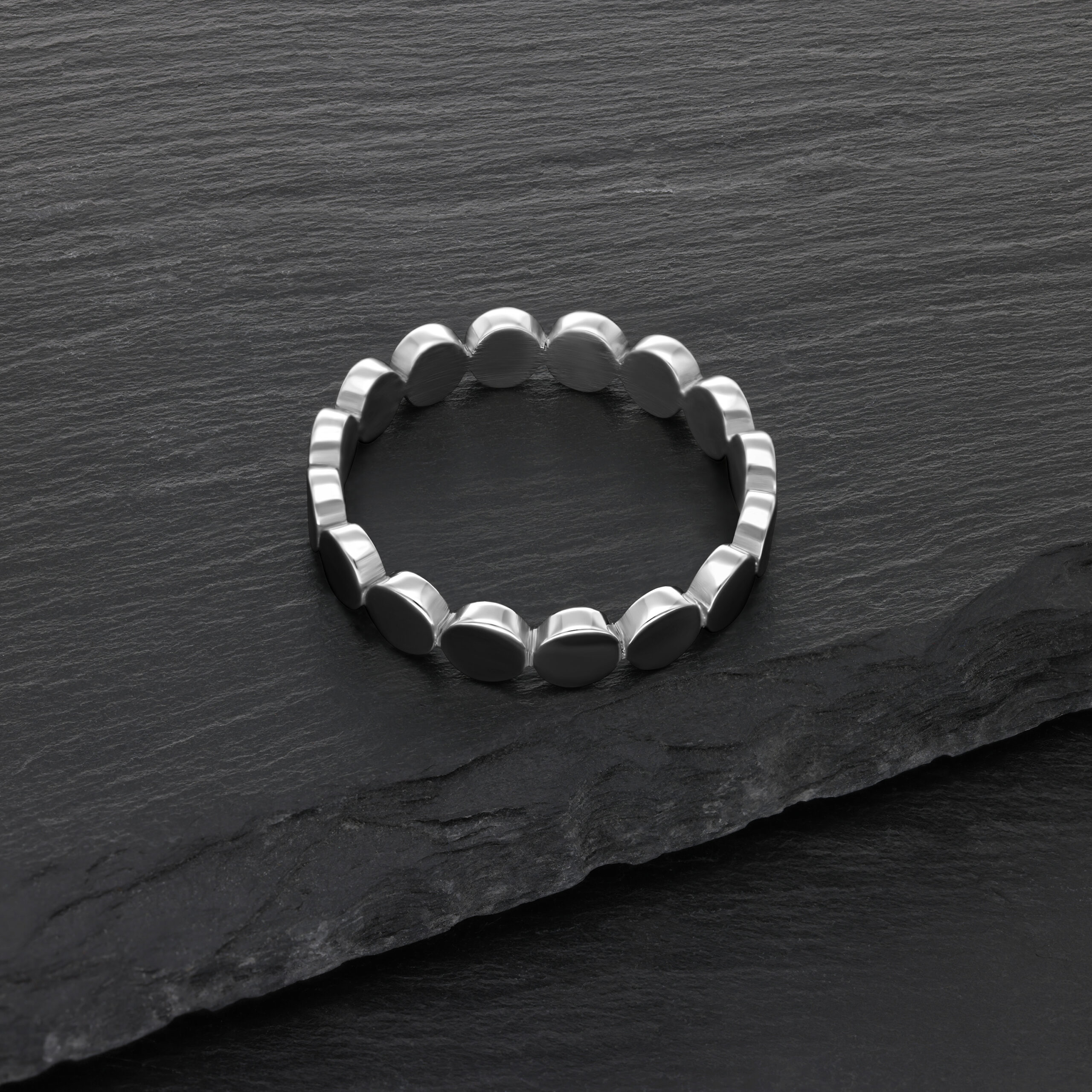 Anello a piastra in acciaio chirurgico argento su sfondo di ardesia nera