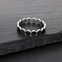 Anello argento in acciaio chirurgico su superficie di pietra scura