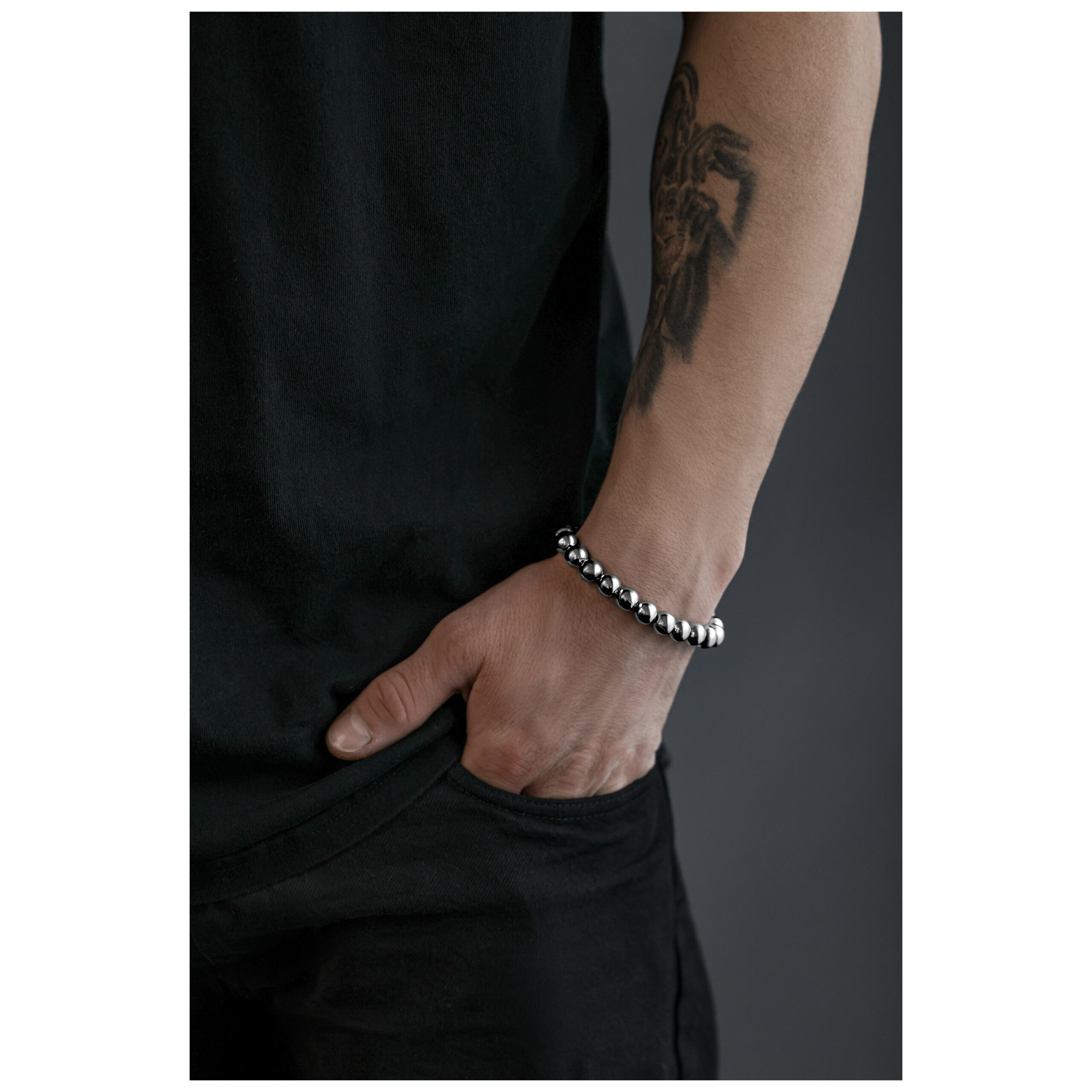 Bracciale Bubble color argento su un polso tatuato davanti a uno sfondo grigio