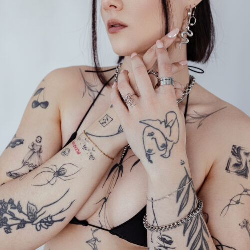 Donna con braccia tatuate che indossa un bracciale intrecciato argento