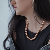 Donna indossa collana Bubble in oro rosa, top nero, giacca grigia
