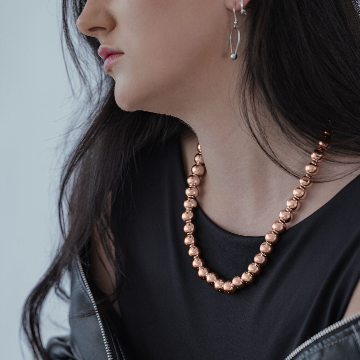 Donna indossa collana Bubble in oro rosa, top nero, giacca grigia