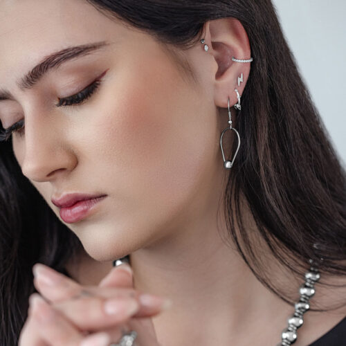 Donna con orecchini a goccia in argento su sfondo grigio