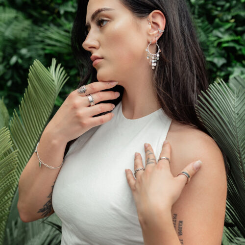 Donna con eleganti orecchini pendenti in acciaio chirurgico in ambiente tropicale