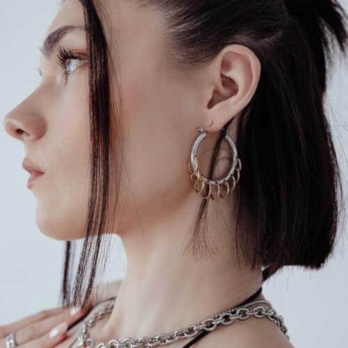 Donna con eleganti hoops massicci con loops in argento e oro su sfondo bianco