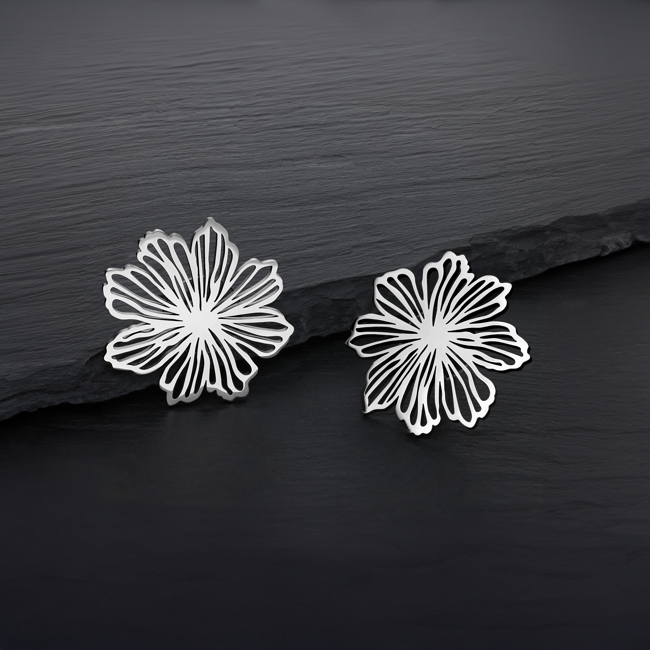 Due orecchini a fiore in argento in acciaio inossidabile su sfondo scuro