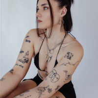 Donna con collana dorata a O in acciaio chirurgico, tatuaggi visibili