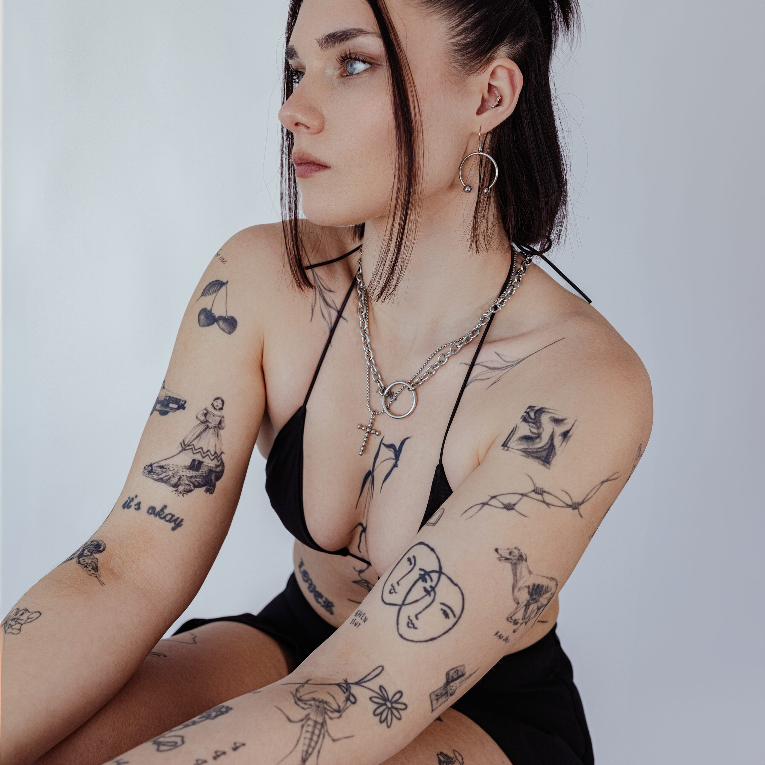 Donna con collana dorata a O in acciaio chirurgico, tatuaggi visibili