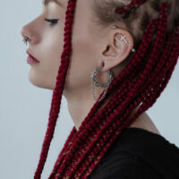 Donna con trecce rosse indossa pesi per orecchie a doppia catena in acciaio chirurgico argentato