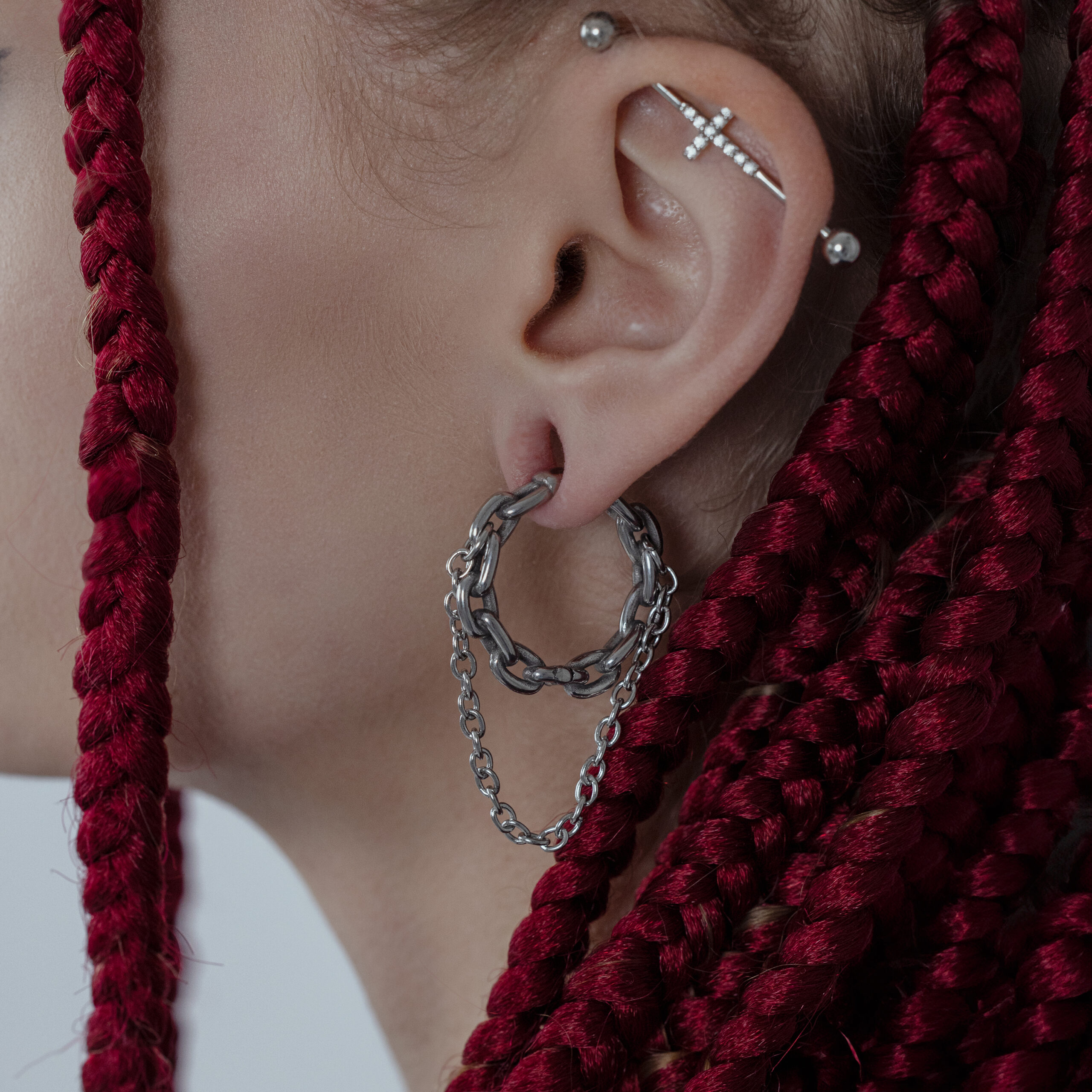 Orecchino a doppia catena in argento su un orecchio con trecce rosse