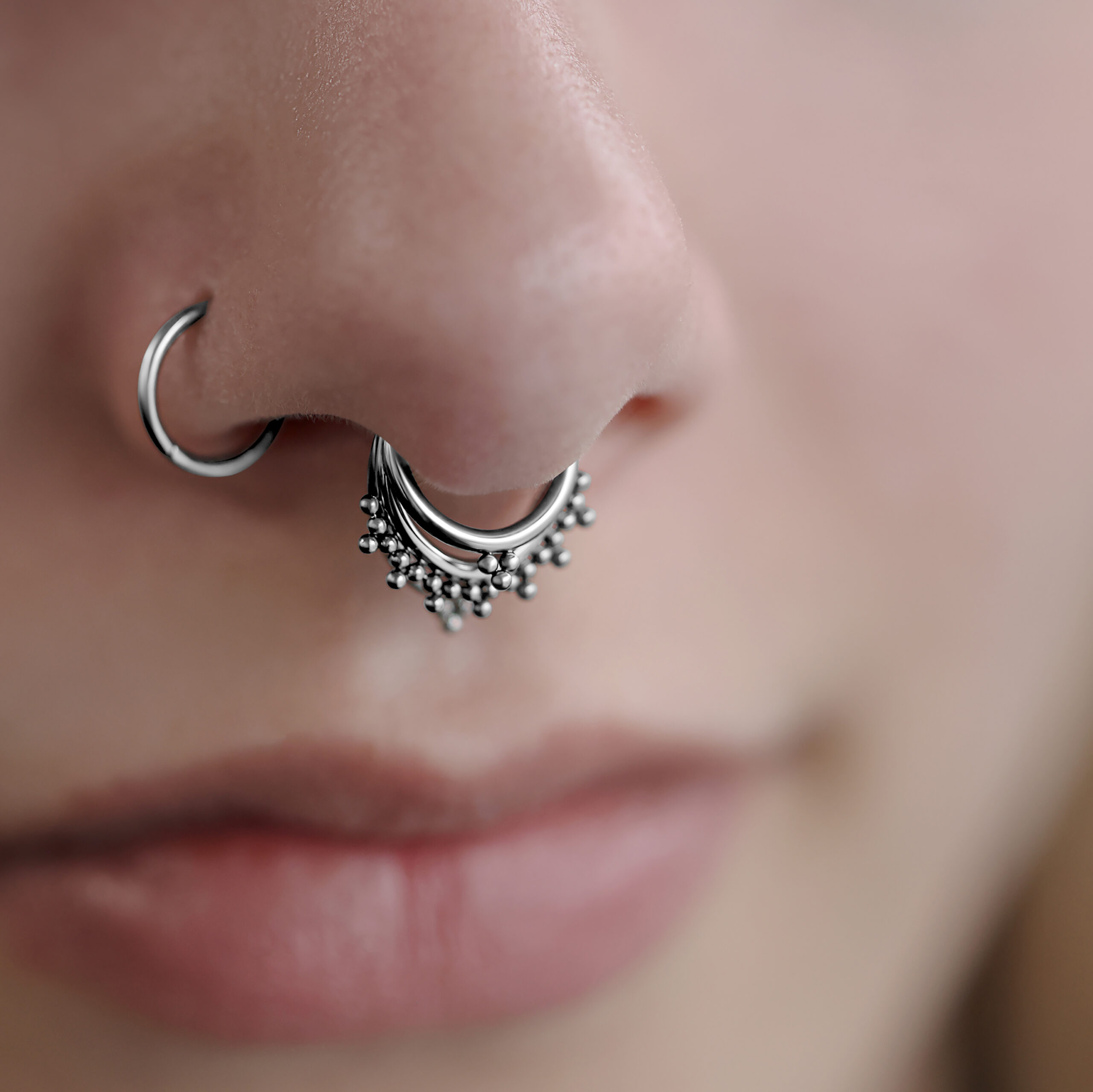 Primo piano di un triplo clicker orientale in argento nel setto di un viso