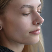 Primo piano di un Triplo Clicker Orientale in argento nel setto di una persona