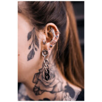 Orecchini Hoops argento e nero su un orecchio con tatuaggi, vista laterale.