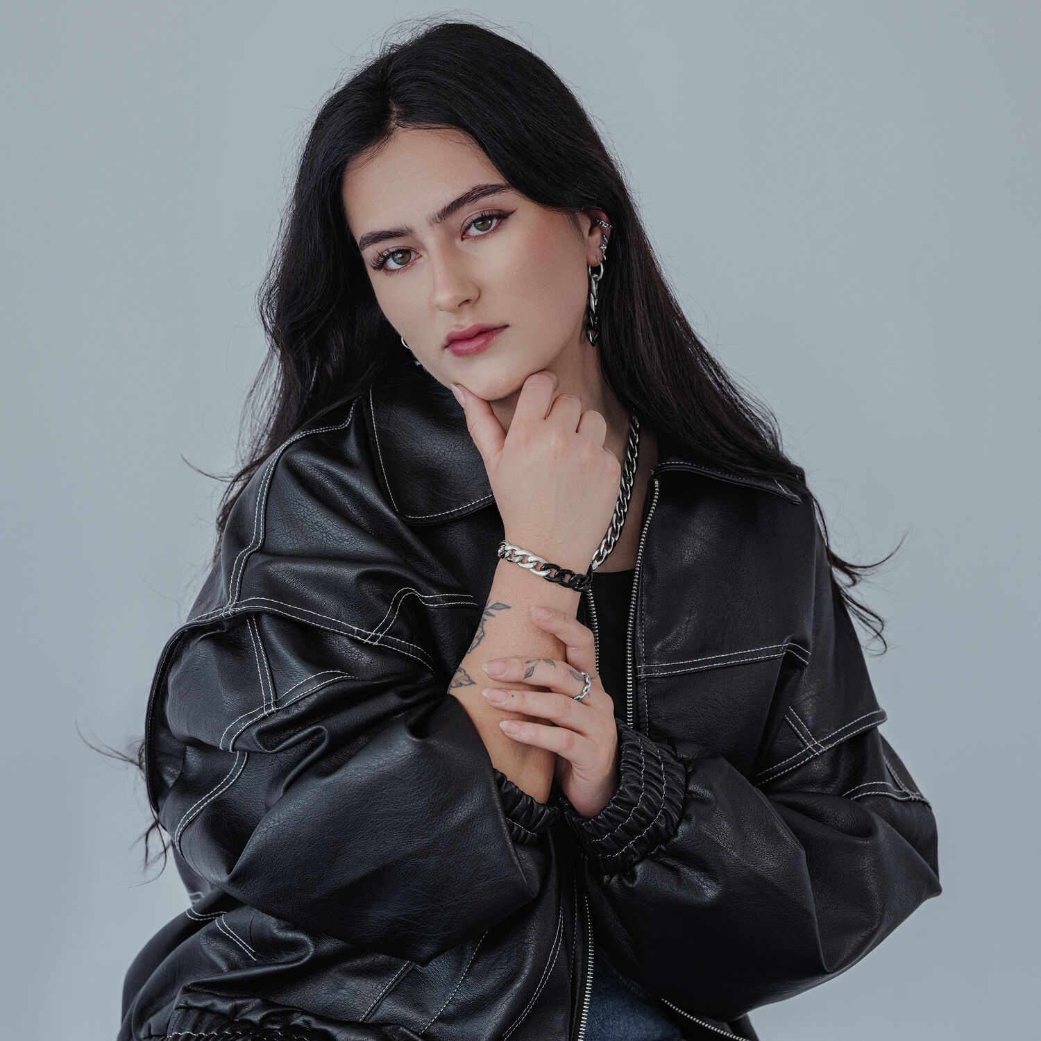 Donna con lunghi capelli neri indossa orecchini in argento di Wildcat su sfondo grigio