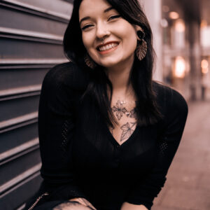 Donna con orecchini Monstera Leaf in metallo argentato davanti a uno sfondo urbano