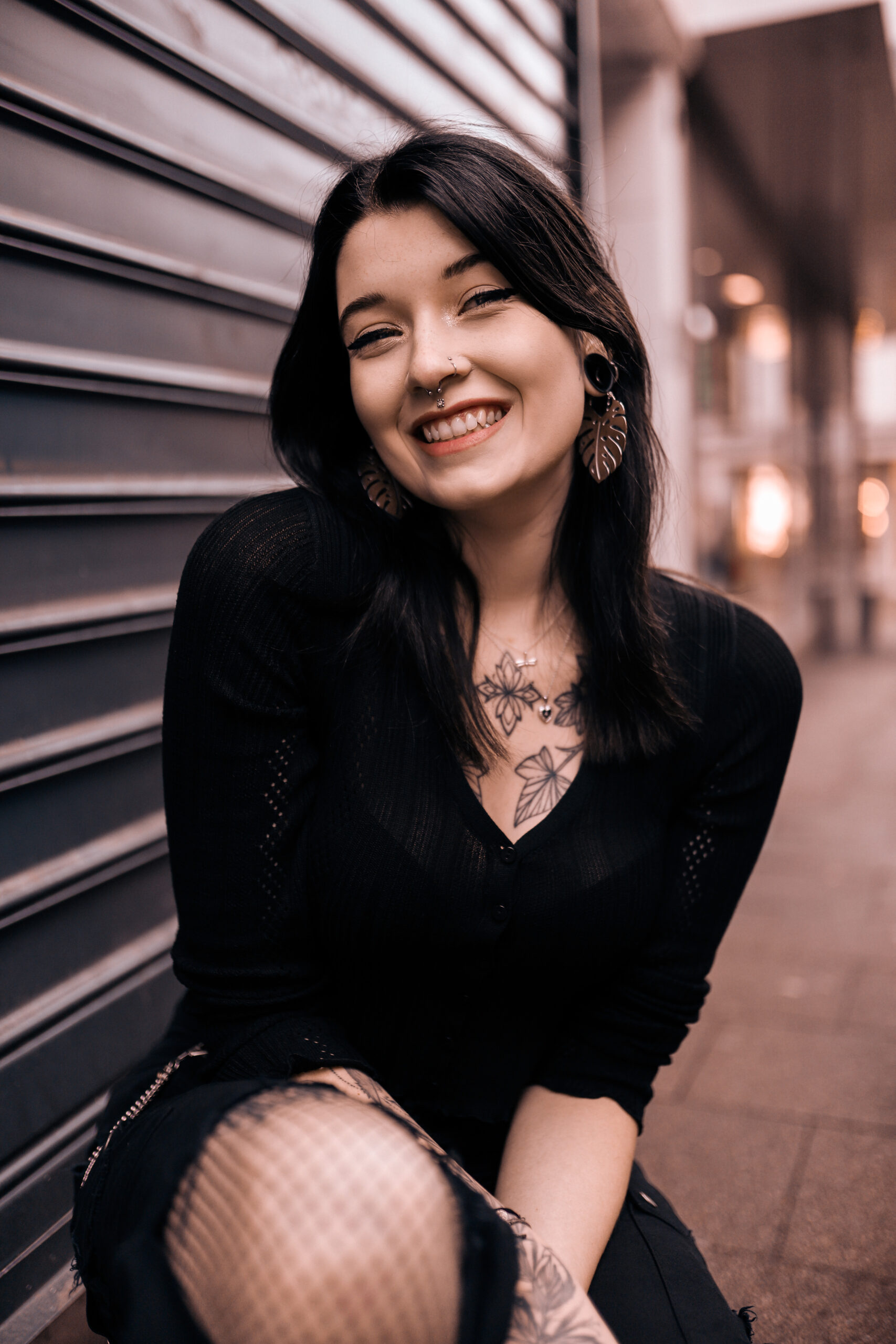 Donna con orecchini Monstera Leaf in metallo argentato davanti a uno sfondo urbano