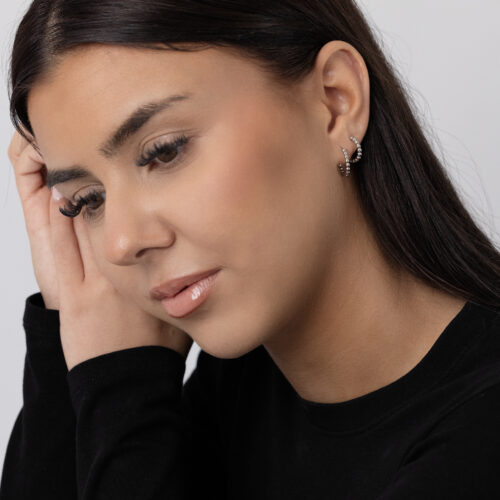 Donna con orecchini Bubble Hoops neri in acciaio inossidabile su sfondo chiaro