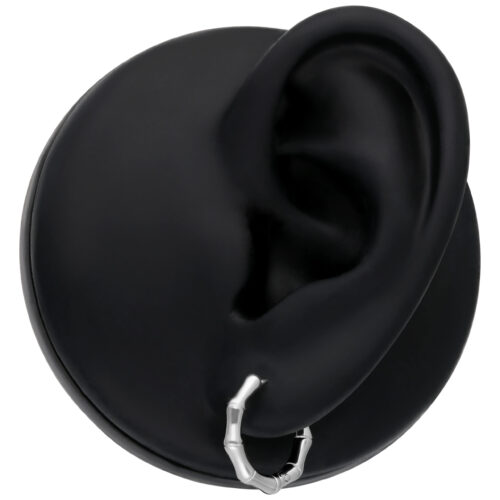 Orecchini in bambù argento su modello d'orecchio nero su sfondo neutro