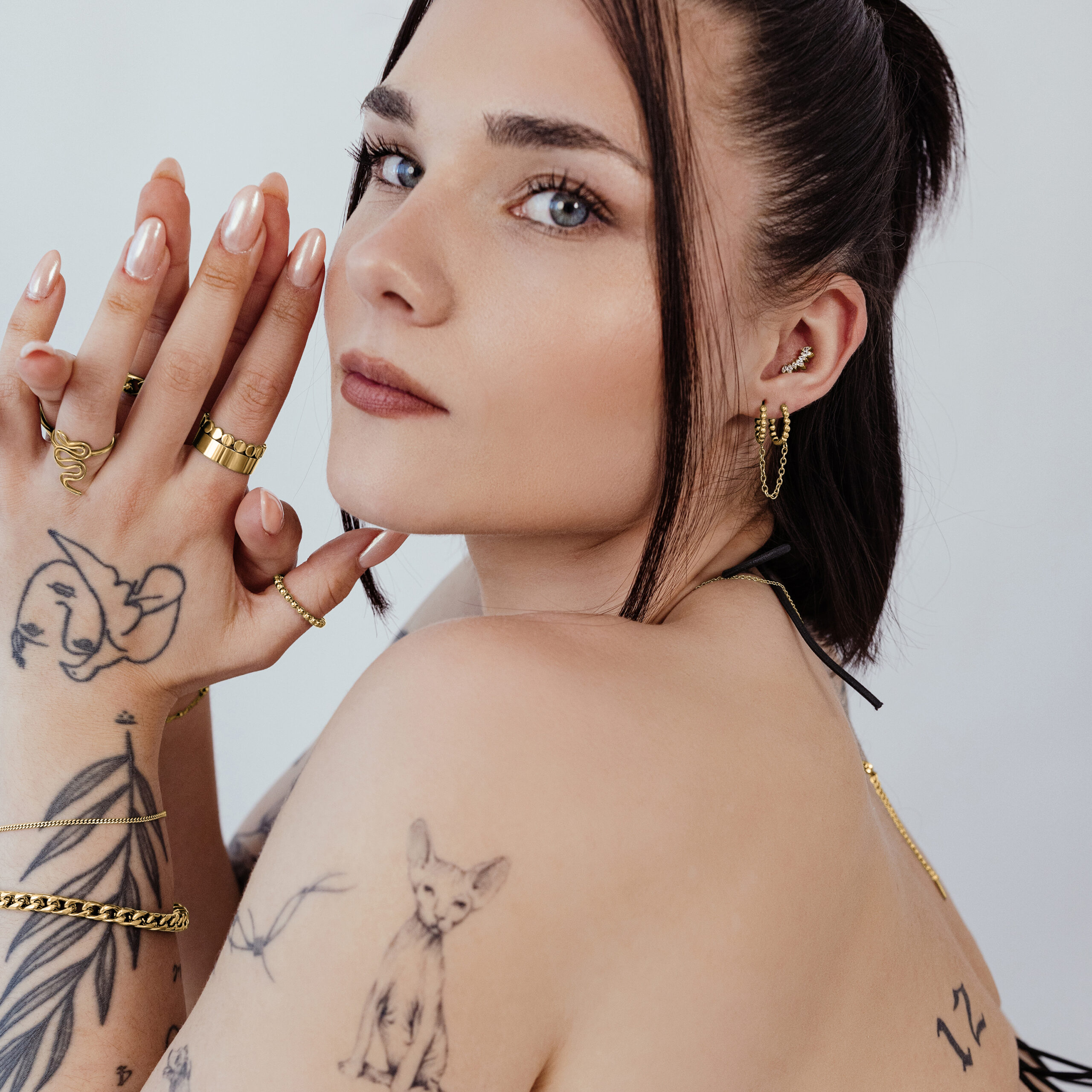 Donna con piercing dorati e tatuaggi, profilo laterale