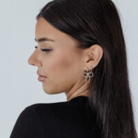 Donna con Little Twisted Bow Hoops in argento su sfondo chiaro