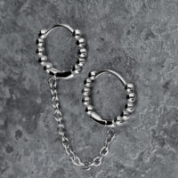 Orecchini doppio Huggie in argento con sfere e catena su sfondo grigio