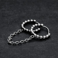 Due anelli piercing Huggie neri collegati con sfere su sfondo scuro
