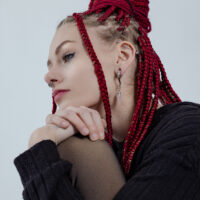 Donna con trecce rosse indossa pesi per orecchie in argento e oro