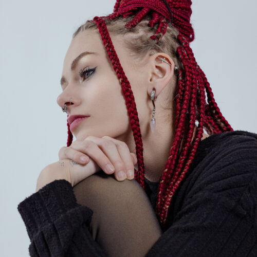 Donna con trecce rosse indossa pesi per orecchie in argento e oro