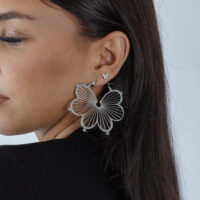 Donna con grande punta a farfalla d'argento nell'orecchio, sfondo nero