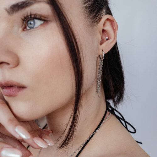 Donna con Push Fit Fiore nell'orecchio, collana e orecchini d'argento, sfondo bianco