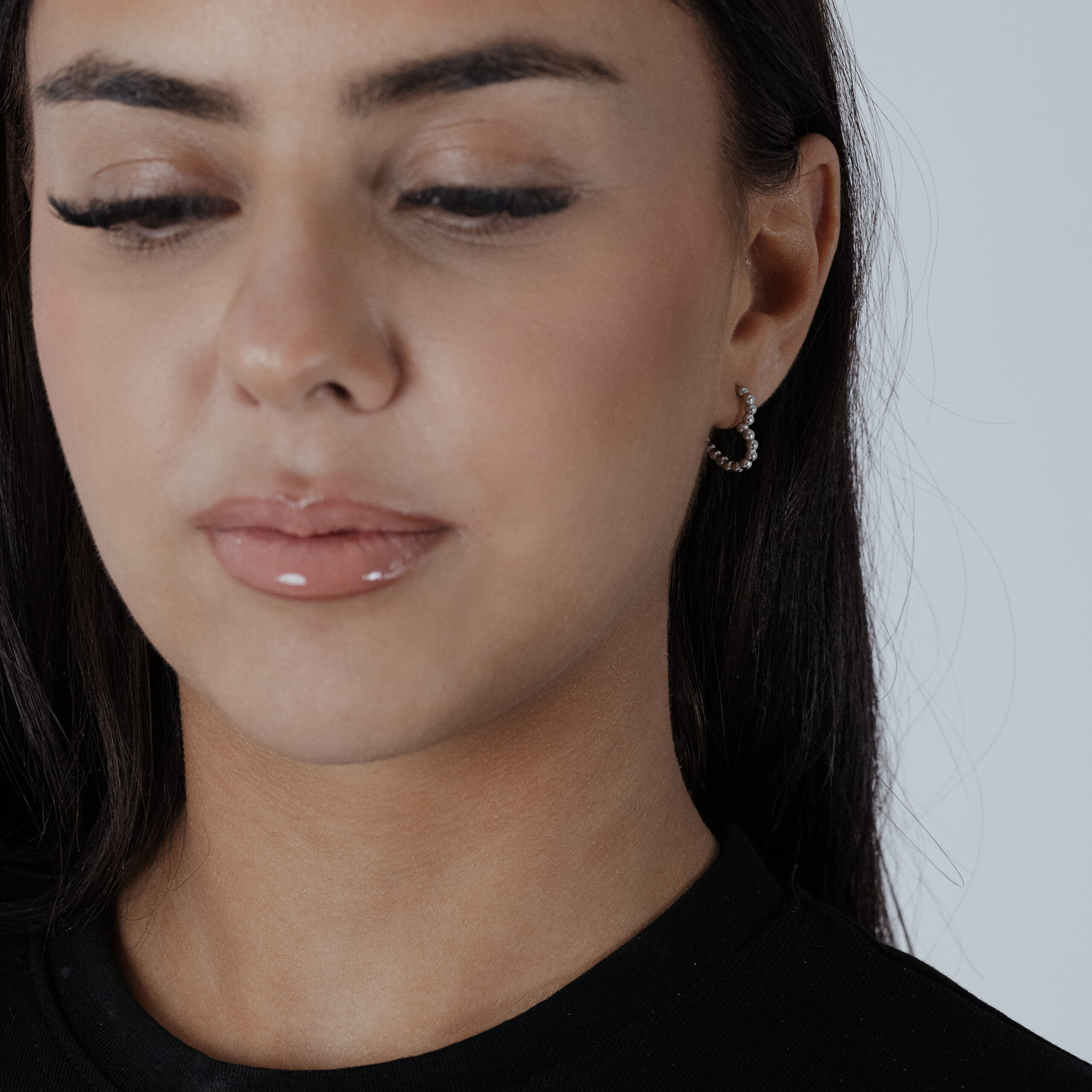 Creole a cuore in argento indossate da una persona con maglia nera