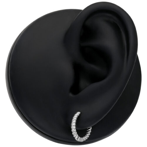 Piccoli orecchini d'argento intrecciati su un modello di orecchio nero su sfondo bianco