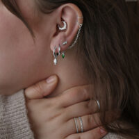 Donna indossa orecchini Little Tear Hoops in acciaio chirurgico in vari colori e dimensioni.